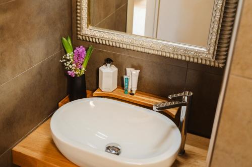 a bathroom sink with a mirror and a vase of flowers at Tenuta Borgo Santa Cecilia in Gubbio