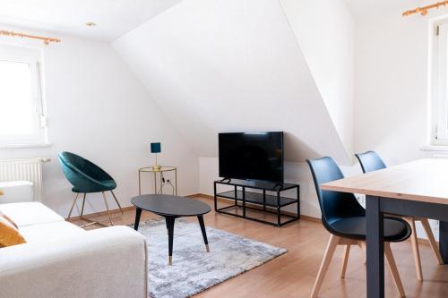 a living room with a tv and a table and chairs at Simplex Stays Heilbronn Louis-Hentges-Str in Heilbronn