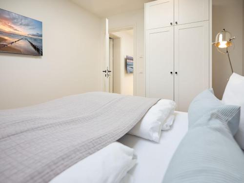 a white bedroom with two beds with white pillows at Appartement Carla in Westerland (Sylt)
