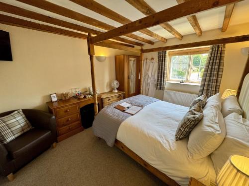 una camera con un letto e una sedia di Guiting Guest House a Guiting Power