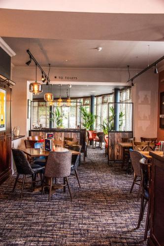 a dining room with tables and chairs and windows at Harper's Steakhouse with Rooms, Haslemere in Haslemere