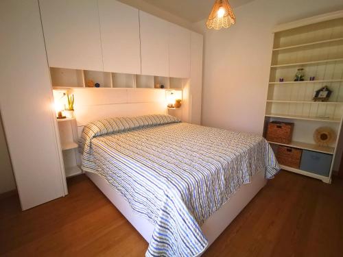 a bedroom with a bed with a striped comforter at Appartament Sunrise 150mt from the beach in Alba Adriatica