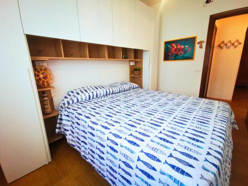 a bedroom with a bed with a blue and white comforter at Appartament Sunrise 150mt from the beach in Alba Adriatica