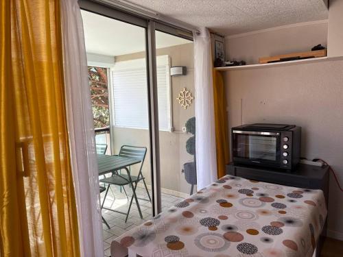 une chambre avec un lit et une télévision et un balcon dans l'établissement Le zéphyr, à Gruissan