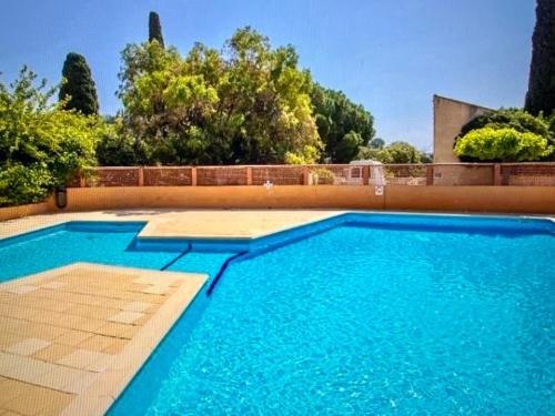 une piscine avec de l'eau bleue devant une maison dans l'établissement Pramousquier -Vue mer - 3 pièces - rénové à neuf, au Lavandou