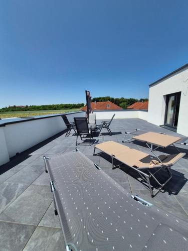 a group of tables and chairs on a roof at Neubauwohnung mit 80 m2 Terrasse, 8 Minuten von Linz entfernt in Linz