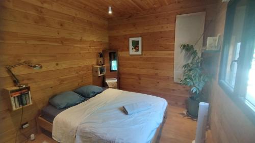 une chambre avec un lit dans une pièce en bois dans l'établissement Le chalet de Paul, à Villevieille