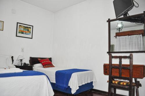 a bedroom with two beds and a chair in it at Hotel Regidor in Salta