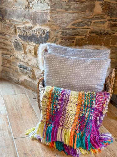 a colorful crochet pillow sitting on a floor next to a wall at Complejo Rural Lar de Vies in A Pontenova