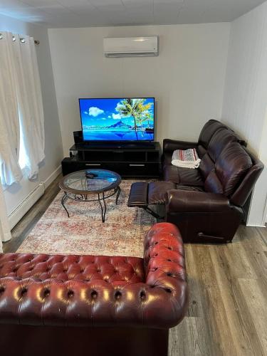 a living room with a leather couch and a flat screen tv at Homefeel Stylish Modern House in Chambord