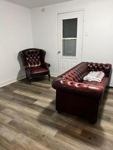 a leather couch and a chair in a living room at Homefeel Stylish Modern House in Chambord