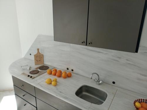 a kitchen counter with a sink and oranges on it at Phil Samosflats Beachfront Maisonettes in Potokáki