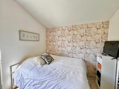 une chambre avec un lit et un mur en pierre dans l'établissement Maison 300m de la plage, à Andernos-les-Bains