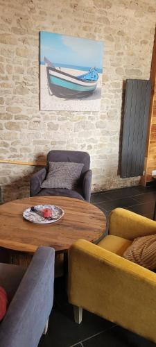 a room with a table and chairs and a picture of a boat at la cabane de chez berthe proche de la plage in Chaucre