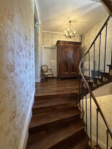 a staircase in an old house with a chandelier at Maison de l'Aumance in Meaulne
