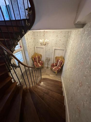 a staircase with two chairs and a chandelier at Maison de l'Aumance in Meaulne