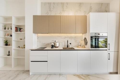 a white kitchen with white cabinets and appliances at Njivice Coastal Oasis in Njivice