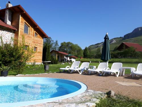 a group of chairs and an umbrella next to a pool at Studiouri Valisoara in Vălişoara