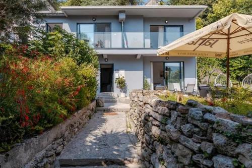a house with a stone wall and an umbrella at Apartments Port View in Herceg-Novi