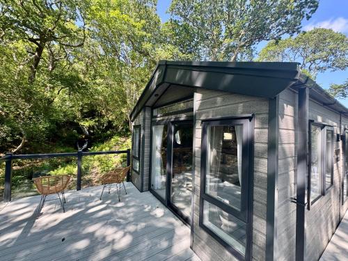 a tiny house with a black roof on a deck at Aberdunant Hall Holiday Park in Porthmadog