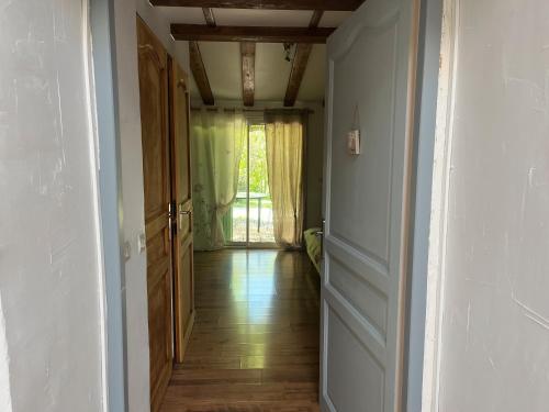 an empty hallway with a door leading to a window at Les Planious in LʼÉpine