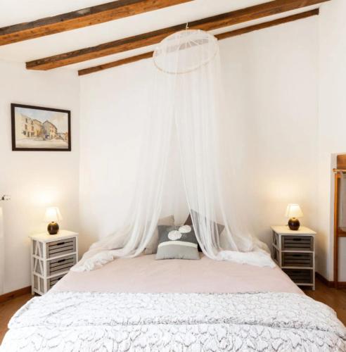 a bedroom with a white bed with a canopy at Les Planious in LʼÉpine