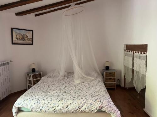a bedroom with a bed with a mosquito net at Les Planious in LʼÉpine