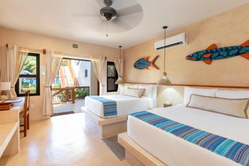 a bedroom with two beds and a desk and windows at Kalimera Beach Hotel in Maya Beach