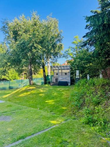 an rv parked in a grassy yard with trees at Apartamenty Wczasowa - z widokiem na góry, parkingiem, rowerownią in Kudowa-Zdrój