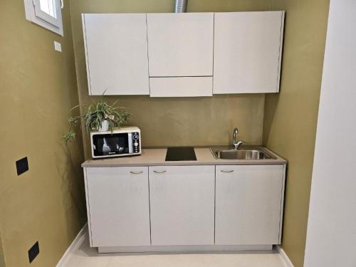 a kitchen with white cabinets and a sink and a microwave at Gabbiano Suites in Cervia