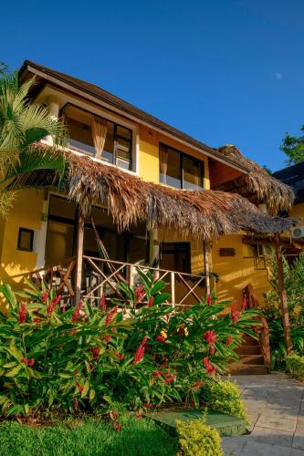 a yellow house with a straw roof at Banana Palms Hotel in Rio Dulce