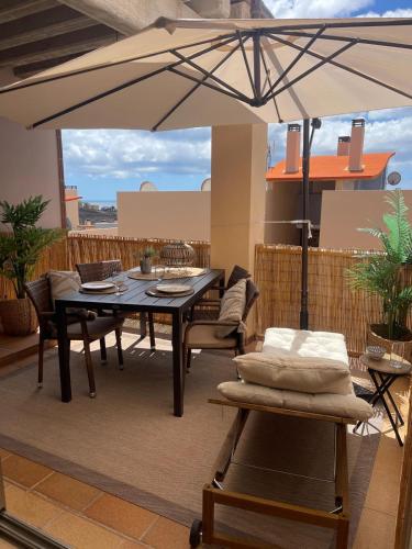 a patio with a table and chairs and an umbrella at Casa Reina in Playa Jandia