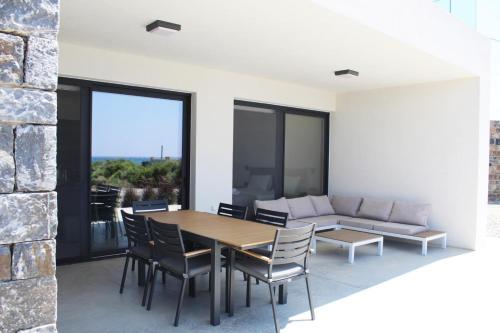 a dining room with a table and chairs and a couch at Astrokastro Seaside Residence in Frangokastello