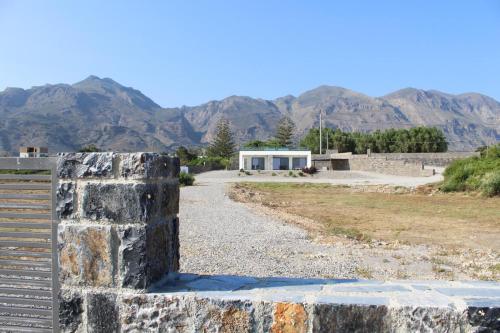 a stone wall with a building and mountains in the background at Astrokastro Seaside Residence in Frangokastello