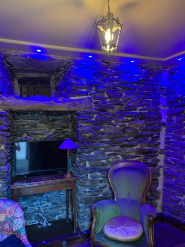 Cette chambre est dotée d'un mur en pierre, d'une chaise et d'une télévision. dans l'établissement Séjournez dans la Tour !, à Ploërmel