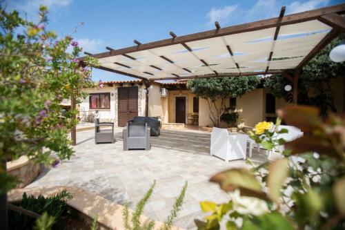 een patio met een pergola en tafels en stoelen bij Le Villette Luisa in Lampedusa