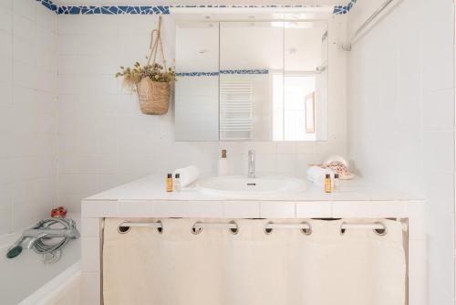 une salle de bain blanche avec un lavabo et un miroir dans l'établissement Veeve - Buttes Chaumont Maisonnette, à Paris