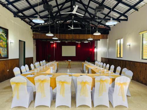 a conference room with tables and white chairs with yellow bows at Hotel Villas del Valle in Valle de Ángeles