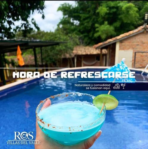a person holding a margarita in a bowl next to a pool at Hotel Villas del Valle in Valle de Ángeles