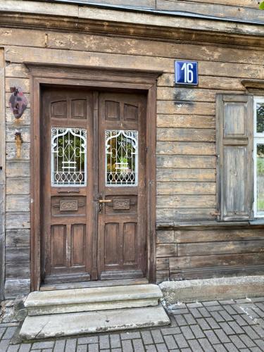 a wooden building with a wooden door with a sign on it at Regina apartment in Ventspils