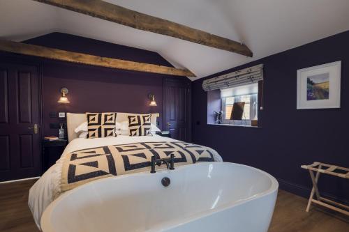 a bedroom with a large bed and a bath tub at The Barrington Boar in Ilminster