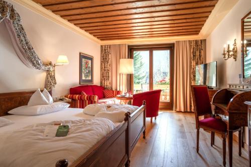 a hotel room with a large bed and a desk at Thermenwelt Hotel Pulverer in Bad Kleinkirchheim