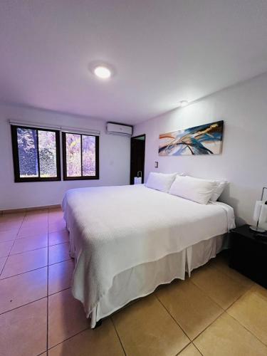 a bedroom with a large white bed and two windows at Casa Vida Villas in Potrero