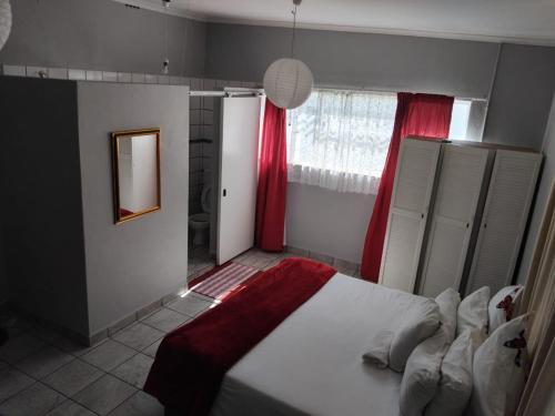 Un dormitorio con una cama y una ventana con cortinas rojas. en Lucian Bed and Breakfast, en Goodwood