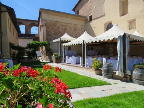 a garden with white tables and white umbrellas and red flowers at Relais Palazzo Paleologi Sec.XIV in Lu