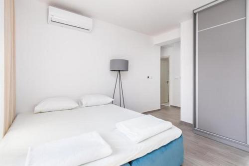 a white bedroom with a bed and a mirror at Apartments Port View in Herceg-Novi