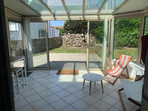 une véranda en verre avec une table et des chaises et un patio dans l'établissement Penty Bretagne, à Penmarcʼh