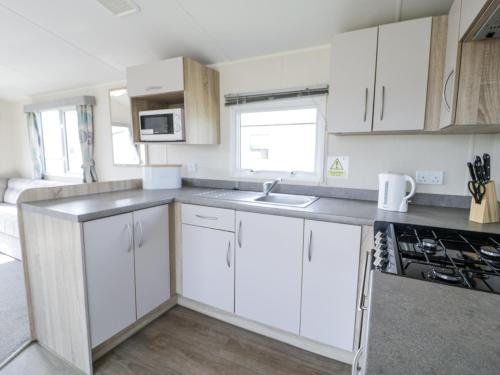 a kitchen with white cabinets and a sink at Manor House Gold 2 Bedroom 20C in Maryport