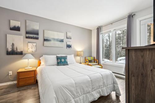 a bedroom with a large white bed and a window at Little Sunshine, Nature retreat, 10min of mountain in Mont-Tremblant