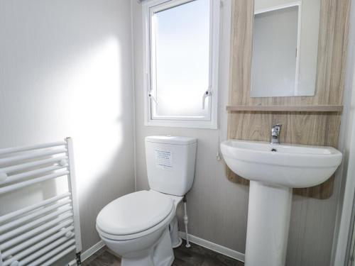 a bathroom with a toilet and a sink and a window at Manor House Platinum 3 Bedroom 16E in Maryport